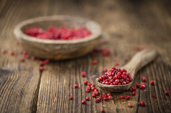 Pink Peppercorns as high detailed close-up shot on a vintage wooden table, selective focus