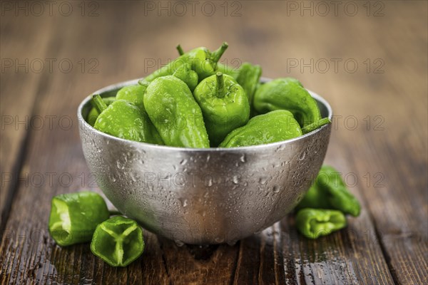 Raw Pimientos on an old wooden table as detailed close-up shot, selective focus