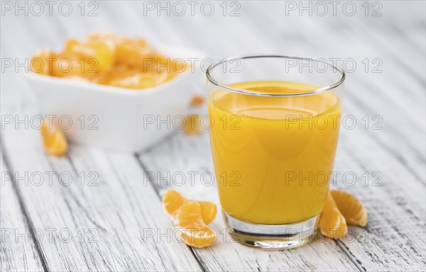 Homemade Tangerine Juice on an old and rustic wooden table (selective focus, close-up shot)