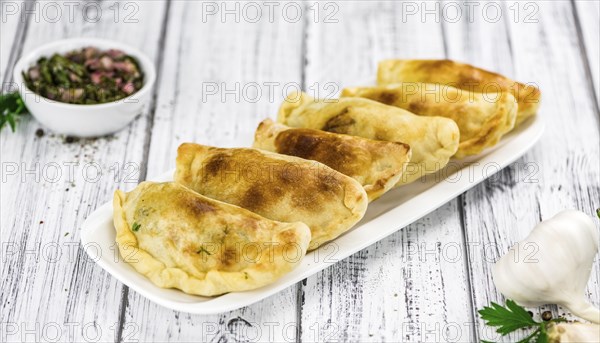 Wooden table with fresh homemade Empanadas (detailed close-up shot, selective focus)