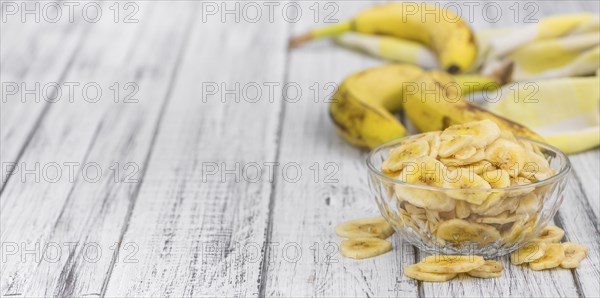 Homemade Dried Banana Chips on an wooden table as detailed close-up shot, selective focus