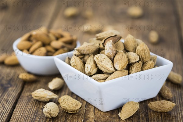 Roasted and salted Almonds (with shell) on a vintage background (close-up shot)