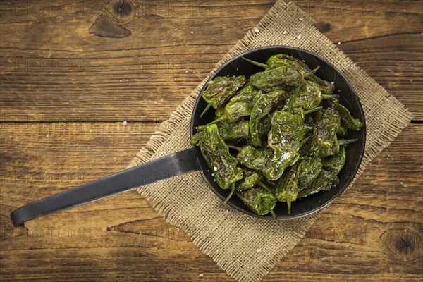 Pimientos de Padron on rustic wooden background as close-up shot