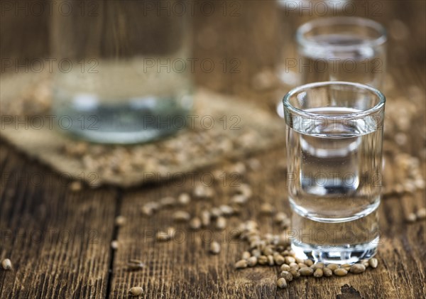 Wooden table with Wheat Liqueur (detailed close-up shot, selective focus)