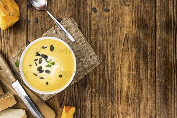 Fresh made Pumpkin Soup (close-up shot) on a vintage background (selective focus)
