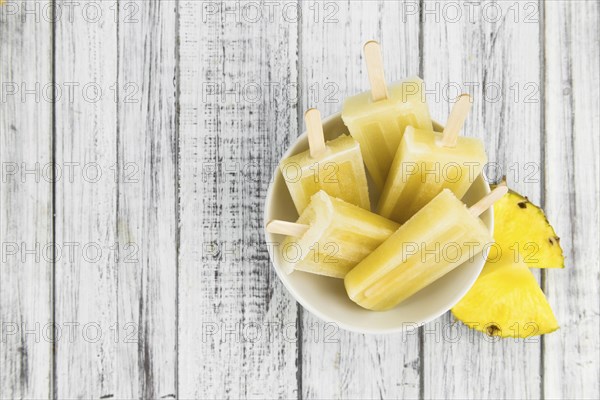 Fresh made Popsicles (Pineapple flavoured, selective focus) on a rustic background