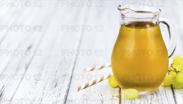 Healthy Grape Juice on a wooden table as detailed close-up shot (selective focus)
