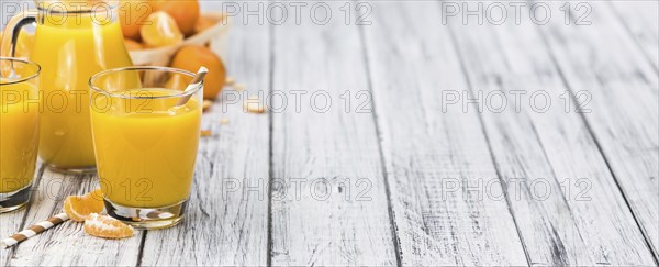 Homemade Tangerine Juice on an old and rustic wooden table (selective focus, close-up shot)