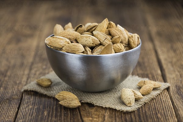 Almonds in shell (roasted and salted) on a vintage background (close-up shot)