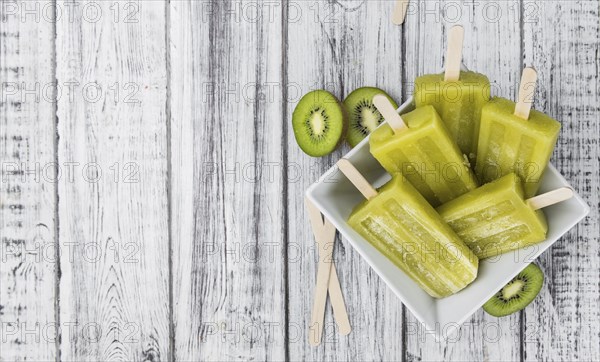 Kiwi Popsicles on an old wooden table (selective focus)