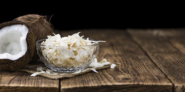Healthy Coconut Flakes on a wooden table as detailed close-up shot (selective focus)