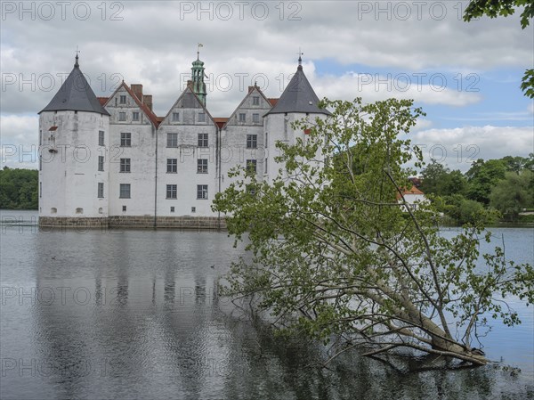 Mighty castle with white walls and striking towers, surrounded by a moat, Glücksburg,