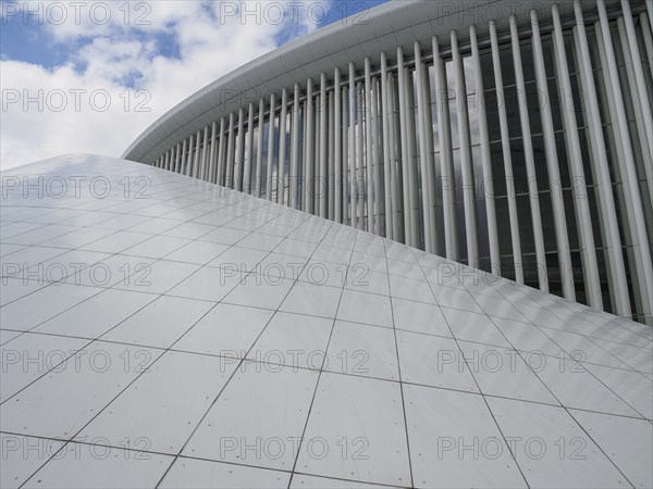 Close-up of a modern building with large windows, vertical struts and glassy structures reflecting