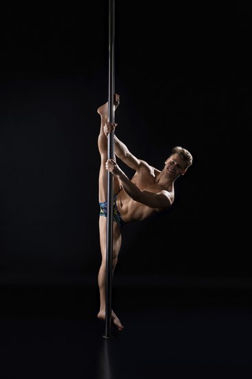 Young fair athletic man exercising on pylon studio shot