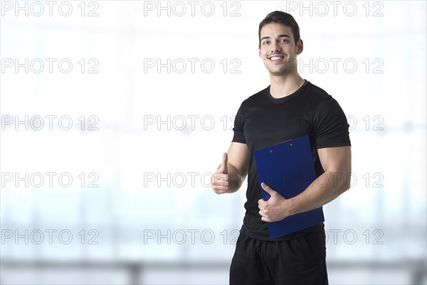 Personal trainer in a gym holding a notepad