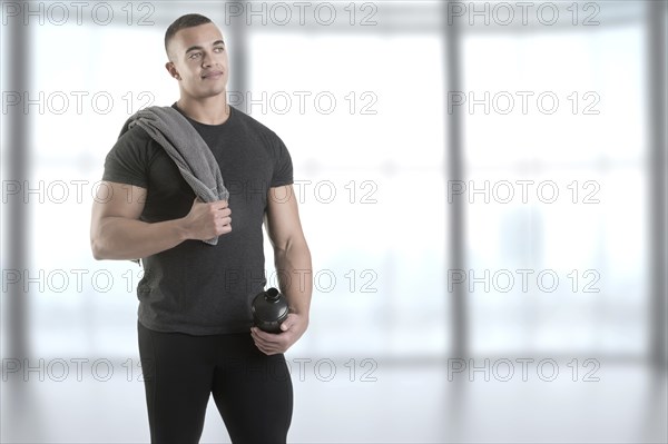 Man holding a protein shake after a workout in the gym