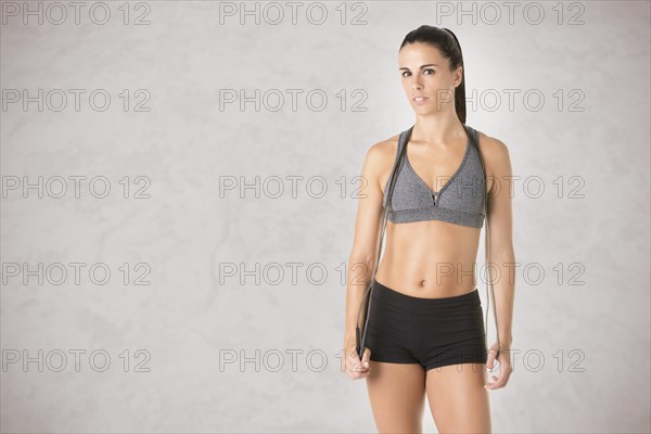 Sporty woman with a jumping rope, isolated in grey