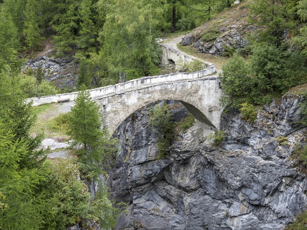 Historic bridge over narrow gorge just below water dam Barrage de Mauvoisin, Val de Bagnes,