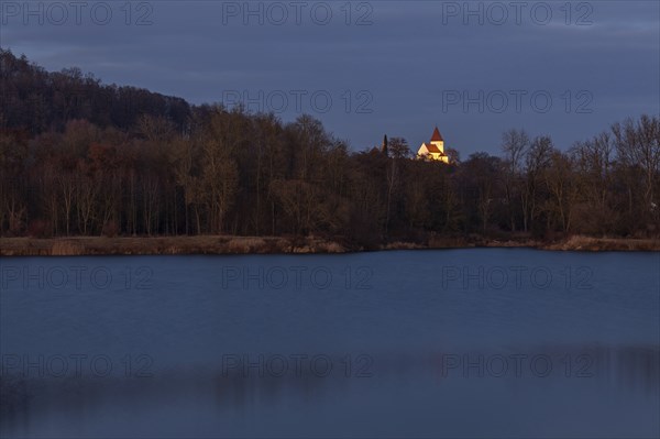 Illuminated church of Schaefstall near Donauworth above a lake in Bavaria