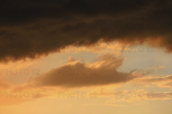 Cloudy sky at sunset. The sky is visible through a gap in the clouds. The image conveys a mood of