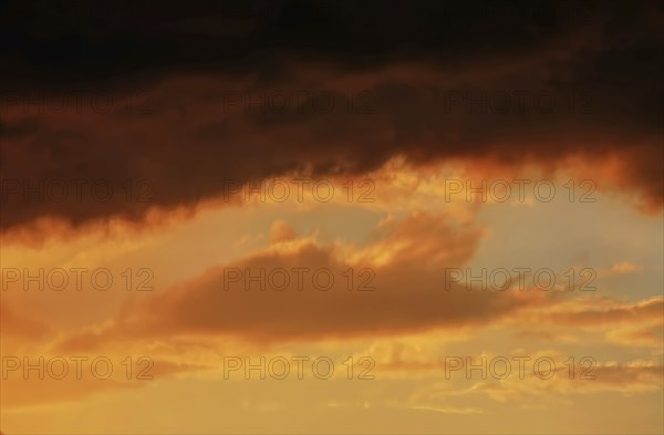 Cloudy sky at sunset. The sky is visible through a gap in the clouds. The image conveys a mood of