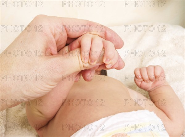 Newborn baby holding onto finger of parent after new diaper