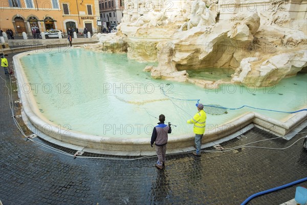 Rome, Italy, January 5, 2018: City workers cleaning coins from Trevi Fountain with water vacuum,