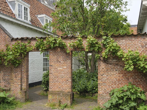 Idyllic garden with green brick arch and surrounding old buildings, Leiden, Netherlands