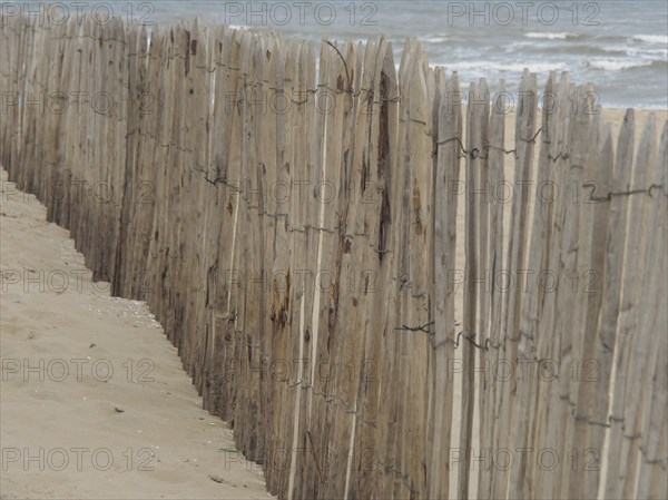 A wooden fence along a beach with a view of the sea, Leiden, Netherlands