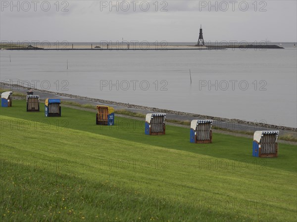 Beach chairs on a green meadow near the sea, with a beacon in the background, cuxhaven, germany