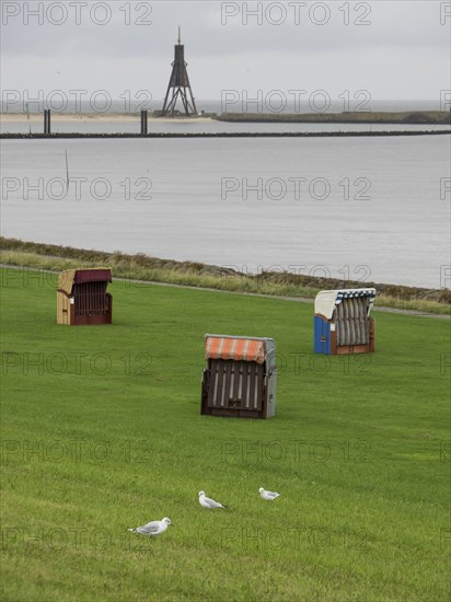Several beach chairs on a green meadow near the sea under a cloudy sky, cuxhaven, germany