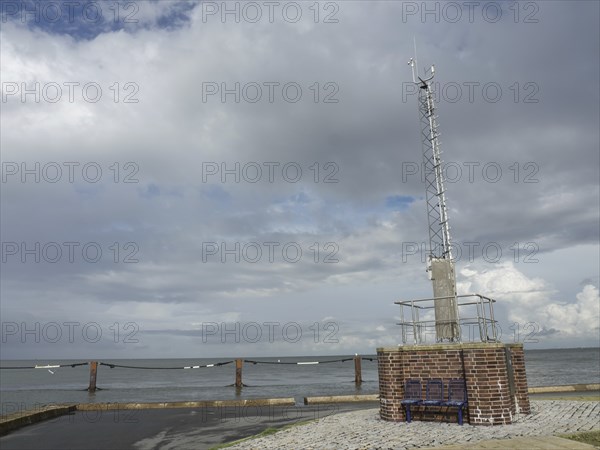 A radio mast on a brick base by the sea under a cloudy sky, cuxhaven, germany