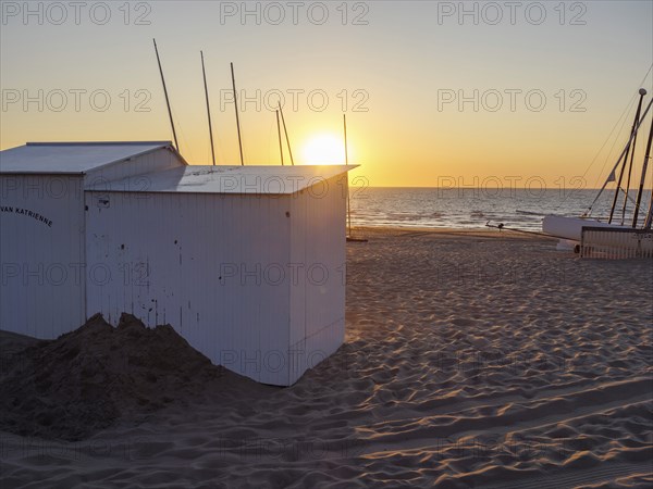 Sunset on the beach with white huts and a boat, warm colours and a calm atmosphere, sea in the