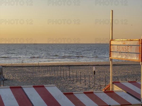 Sunset on the beach with a sign indicating the beach section, De Haan, Flanders, Belgium, Europe