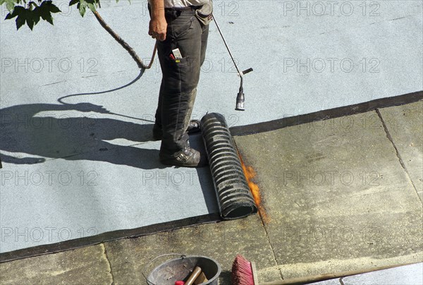 Roofer with a gas burner on a roof