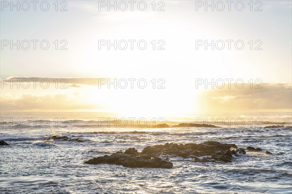 Sunrise over the sea with gentle waves. Sandy beach with lava rocks and blue water alternating with