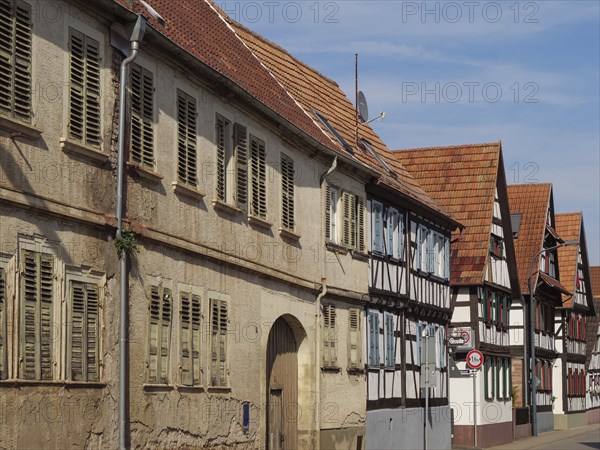 Row of old half-timbered houses with red roofs and shutters along a sunny street, Kandel,
