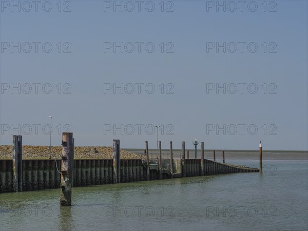 Quiet harbour with wooden piles and a clear sky over the sea, hallig hooge, schleswig-holstein,