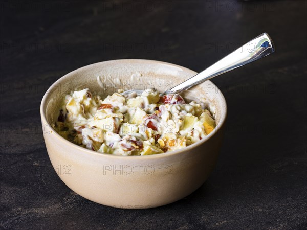 Fresh homemade muesli with organic fruit and rolled oats mixed in natural yoghurt in a ceramic bowl