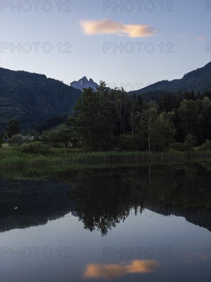 Evening clouds reflected in the lake, mountain peak of Admonter Reichenstein in the background,