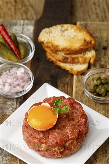 Steak tartare with open egg on wood