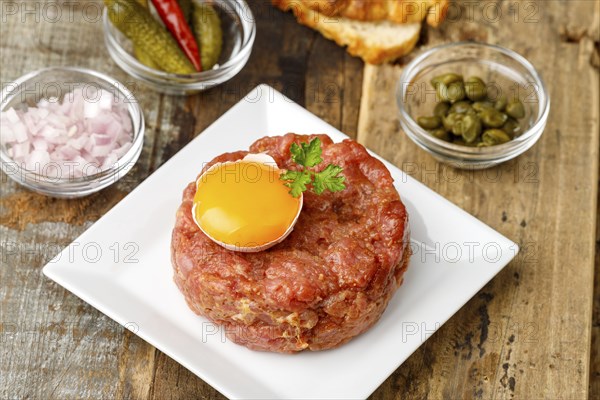 Steak tartare with open egg on wood
