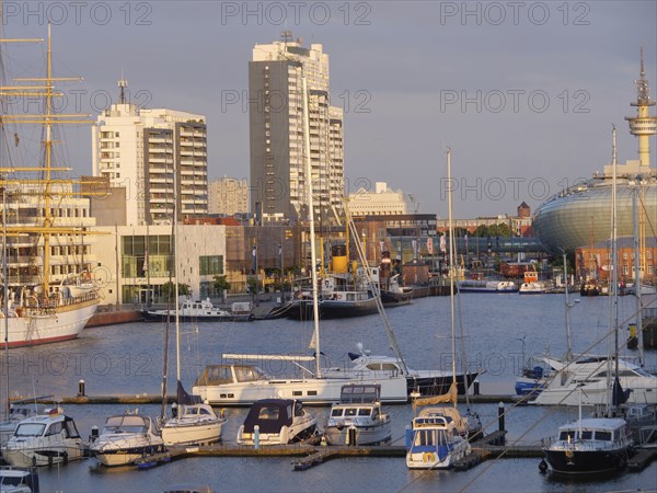 Harbour view with several yachts and boats in front of a city backdrop of skyscrapers in the