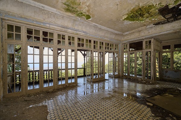 Abandoned room with broken windows, dilapidated floor and view of the green nature, Mussolini