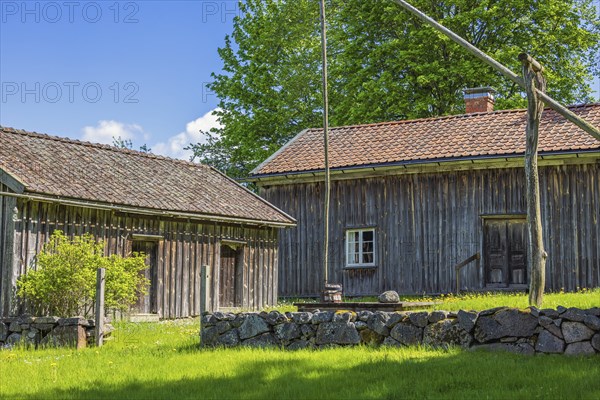 Rustic old farm with wooden house a water well and a stone wall in the swedish countryside, Suntak,
