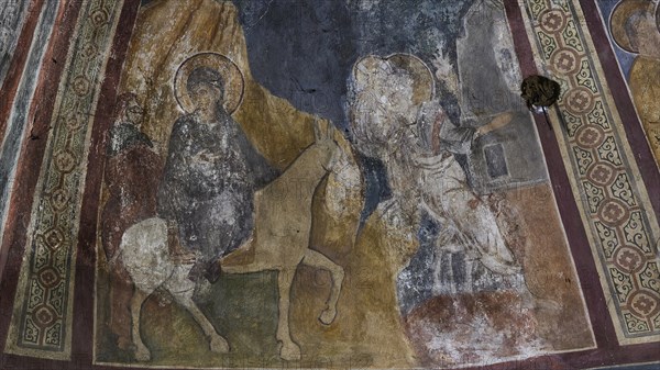 Wall painting showing a holy horseman and an angel in a church, weathered and partially damaged,