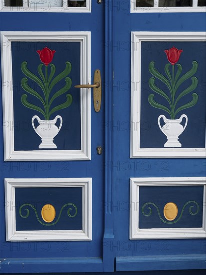 Close-up of a blue and white decorated door with tulip pattern and golden door handle, ahrenshoop,