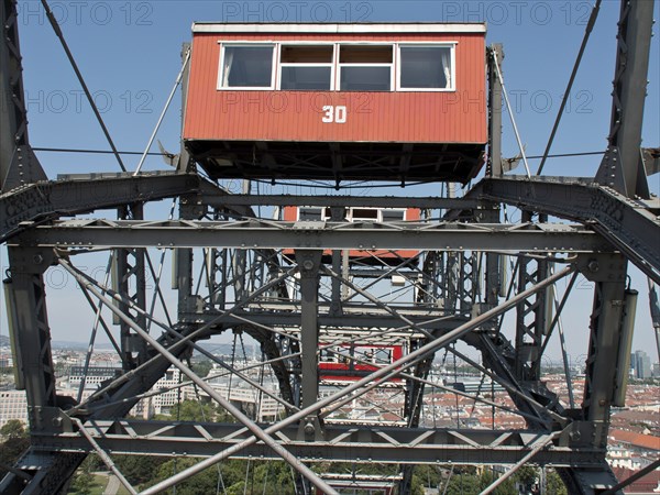 Detailed view of a red cabin of a Ferris wheel with a view of the city in the background, Vienna,