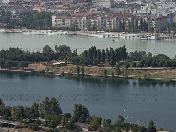 View of a riverside town with park-like areas, trees and residential buildings in the background,