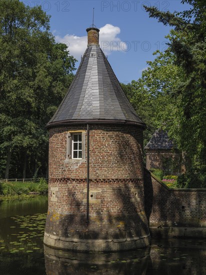 Brick round tower with lead-grey roof on a moat, surrounded by summer nature, ochtrup, münsterland,